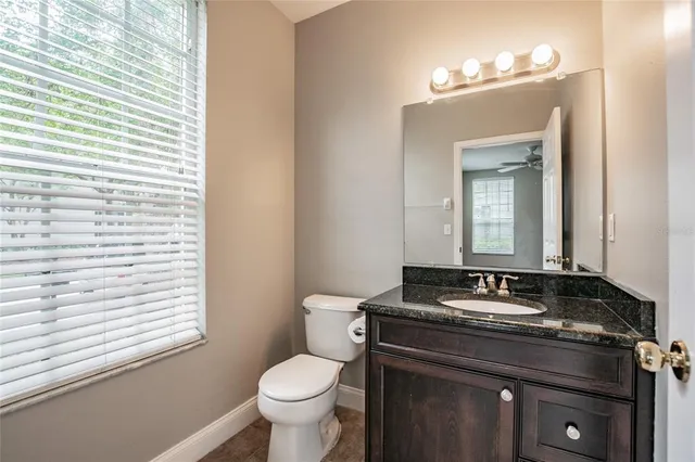 a bathroom with a granite countertop sink toilet and mirror