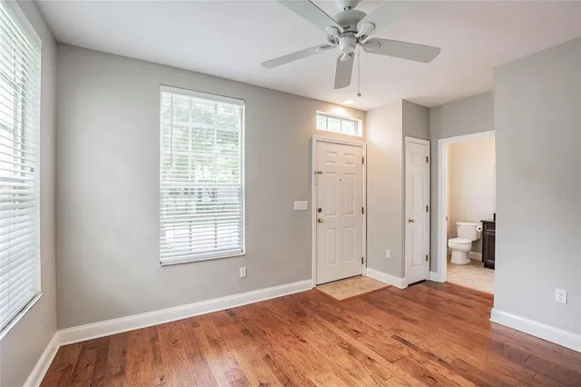 a view of empty room with wooden floor and fan