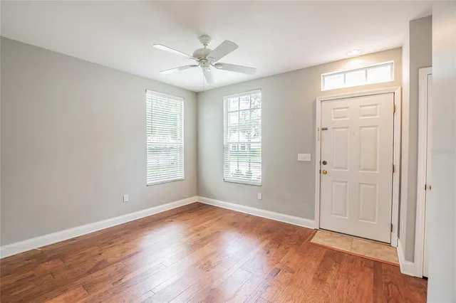 a view of an empty room with wooden floor and a window