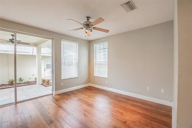 an empty room with wooden floor fan and windows