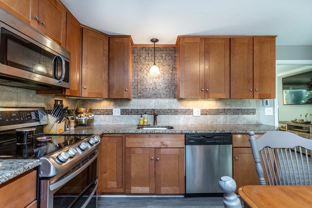 9 Village Way, Unit F Norton, MA 02766 - Photo 7 of 20 a kitchen with stainless steel appliances granite countertop a stove a sink dishwasher and a microwave oven with wooden floor