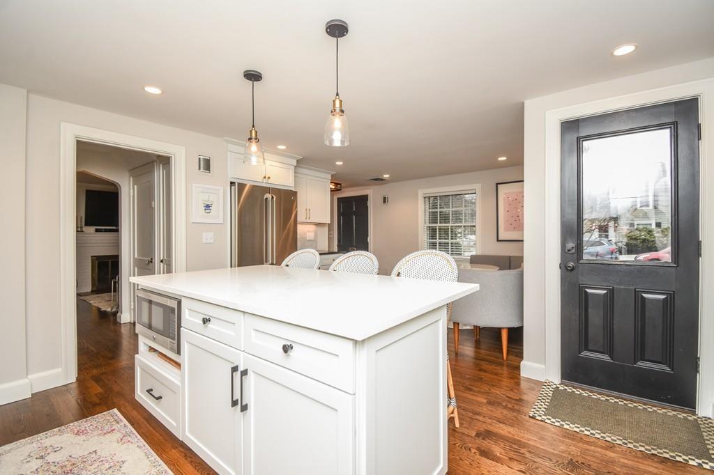 21 Lancaster Road Needham, MA 02492 - Photo 2 of 35 a large white kitchen with kitchen island a refrigerator a stove a sink dishwasher with a dining table and chairs