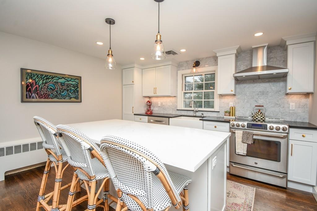 21 Lancaster Road Needham, MA 02492 - Photo 3 of 35 a kitchen with a stove a sink a kitchen island with chairs and wooden floor