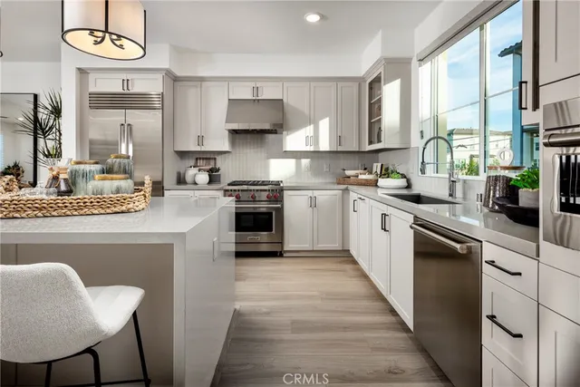 a kitchen with stainless steel appliances granite countertop a sink a stove a refrigerator cabinets and chairs