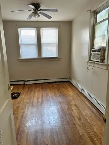 an empty room with wooden floor fan and windows