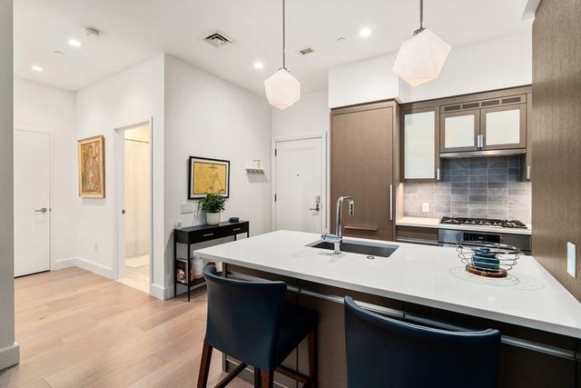 a kitchen with a sink a stove a refrigerator and white cabinets with wooden floor