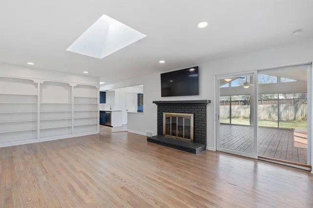 an empty room with wooden floor and a fireplace