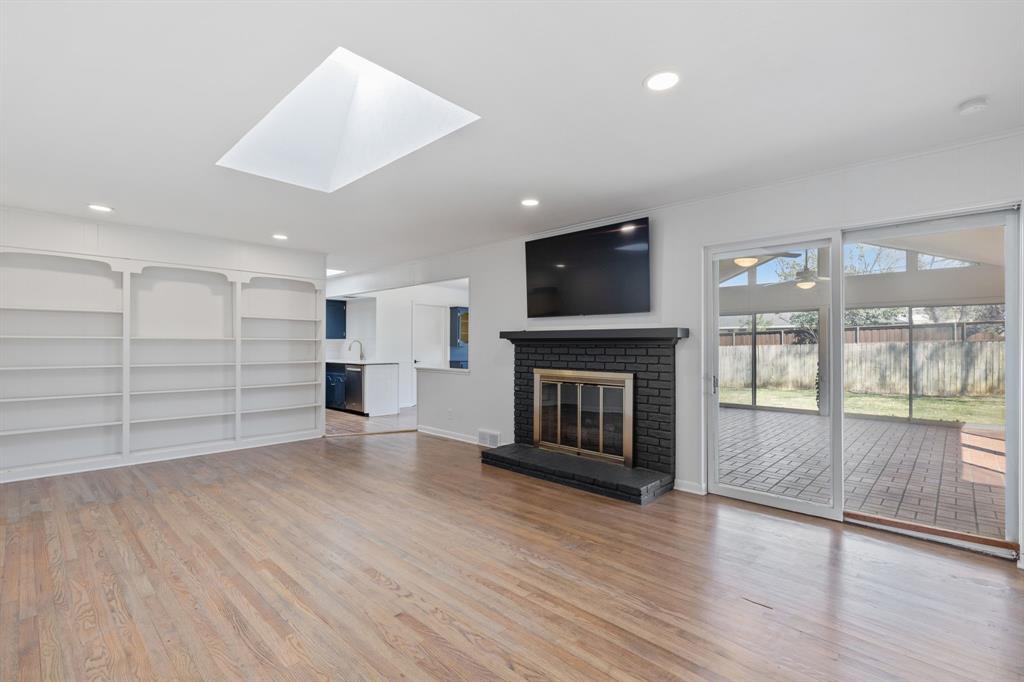 10510 Gooding Drive Dallas, TX 75229 - Photo 7 of 14 an empty room with wooden floor and a fireplace