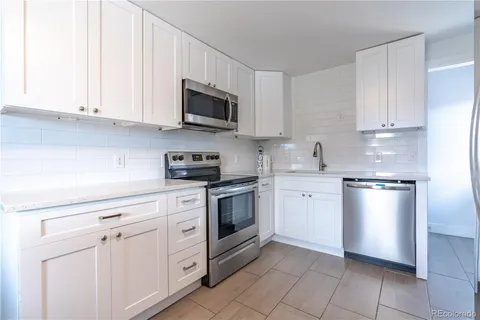 a kitchen with white cabinets and stainless steel appliances