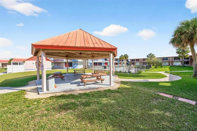 a view of a patio with dining table and chairs with plants and palm trees