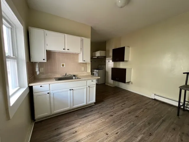a kitchen with kitchen island white cabinets and wooden floor