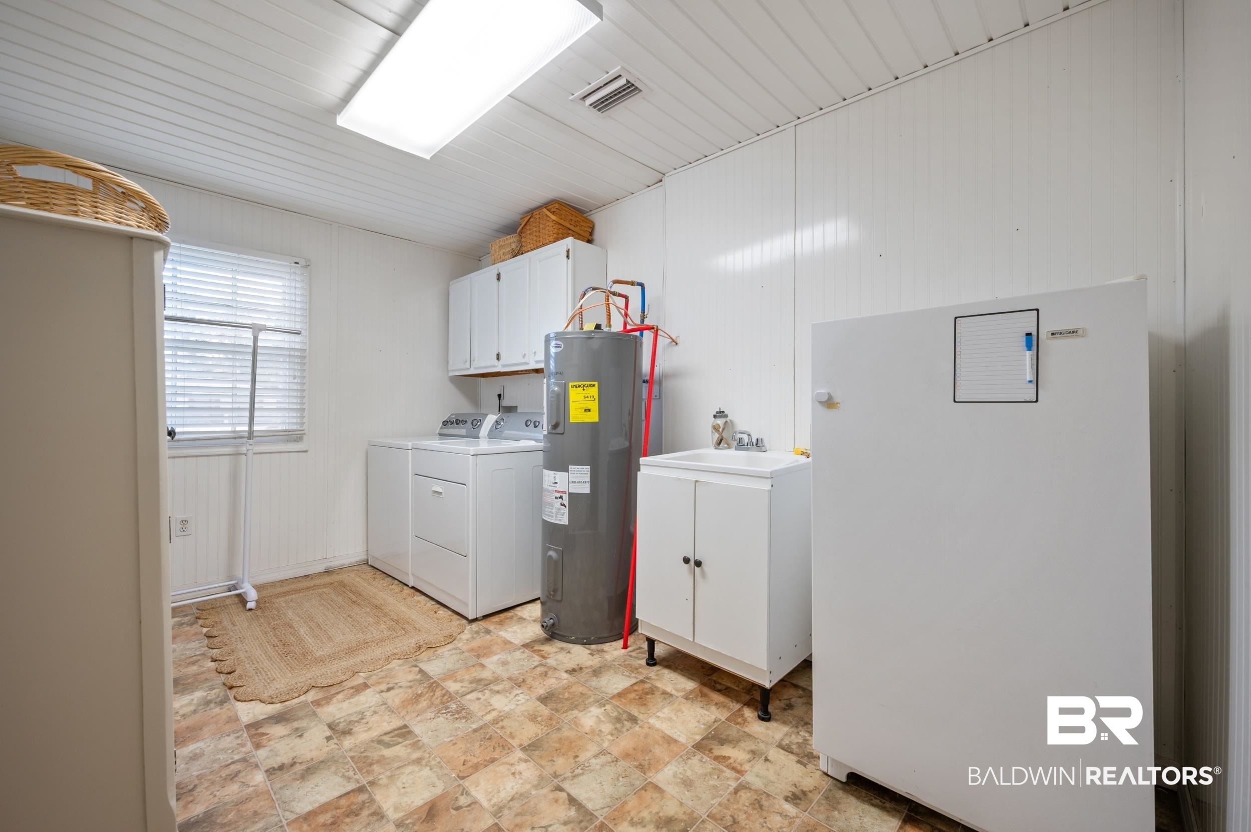 809 Moog Avenue Bay Minette, AL 36507 - Photo 26 of 33 Laundry room featuring cabinet space, washer and clothes dryer, water heater, and stone finish floors