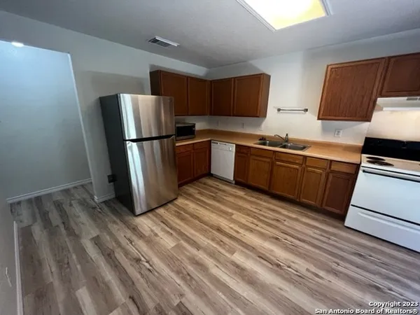 a kitchen with stainless steel appliances granite countertop a refrigerator a stove top oven a sink and dishwasher