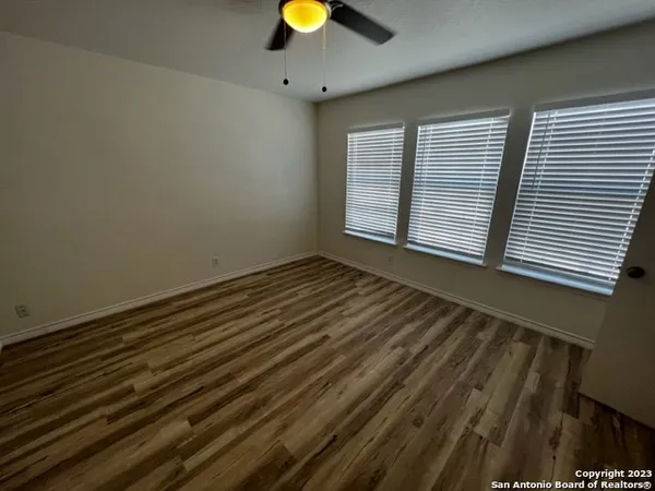 a view of an empty room with window and chandelier fan