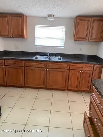 a kitchen with granite countertop a sink a stove top oven cabinets and a window