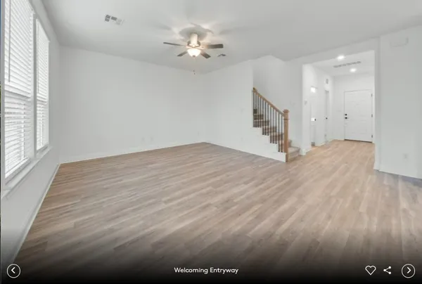 a view of an empty room with wooden floor and stairs