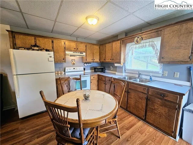 a kitchen with stainless steel appliances granite countertop a dining table chairs refrigerator a sink and dishwasher