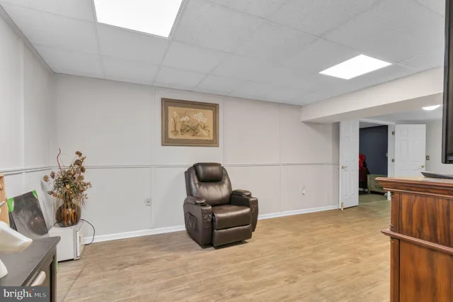 a living room with furniture a flat screen tv and a refrigerator