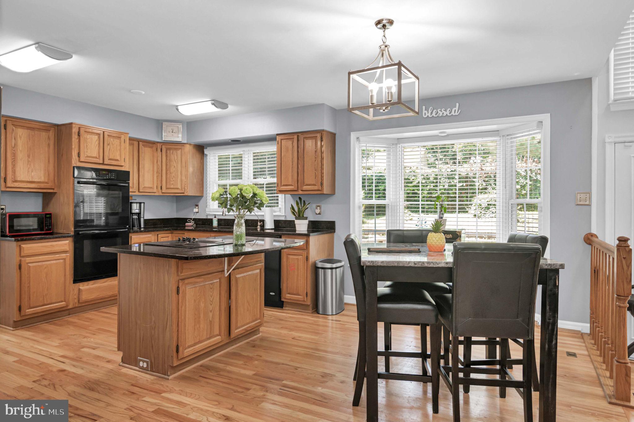 10404 Amherst Circle Fredericksburg, VA 22408 - Photo 55 of 74 a kitchen with stainless steel appliances granite countertop a stove a sink dishwasher a dining table and chairs with wooden floor