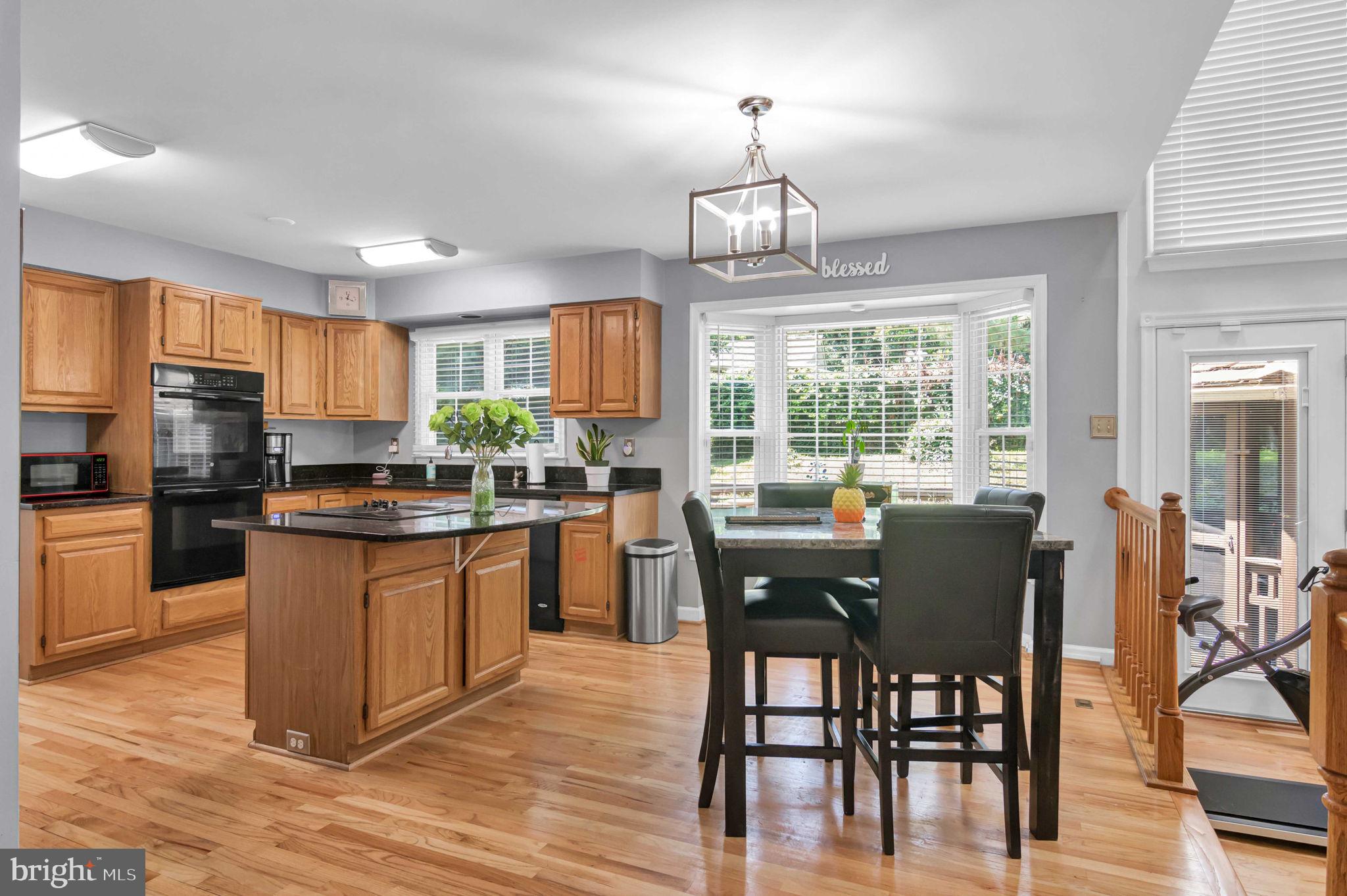 10404 Amherst Circle Fredericksburg, VA 22408 - Photo 57 of 74 a kitchen with stainless steel appliances granite countertop a stove top oven a sink dishwasher a dining table and chairs with wooden floor