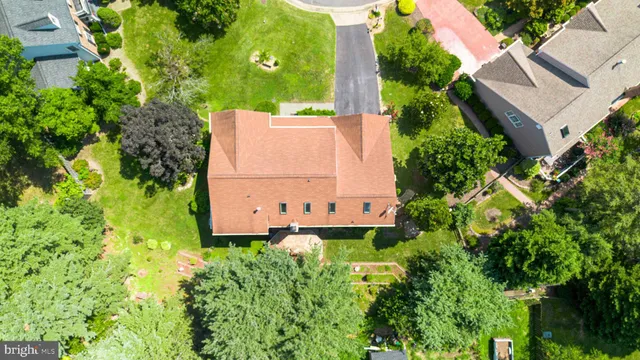 a view of a house with a small yard plants and large trees