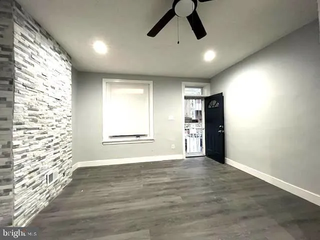 a view of an empty room with a window and wooden floor