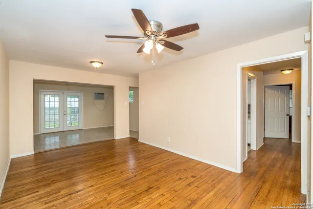 a view of an empty room with wooden floor and a window