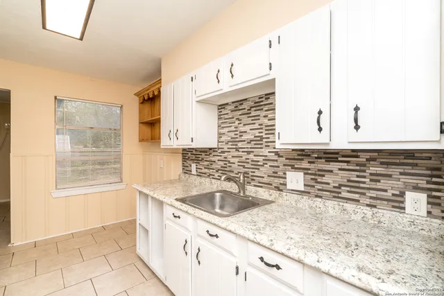 a kitchen with granite countertop a sink a stove and cabinets