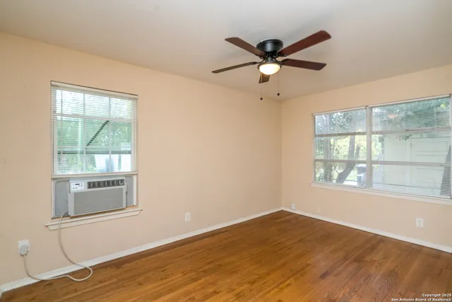 a view of empty room with wooden floor and fan