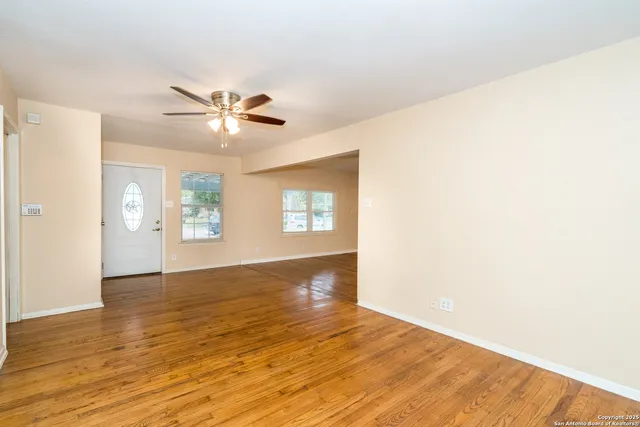 a view of an empty room with window and wooden floor