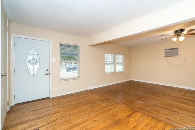 a view of empty room with wooden floor and fan