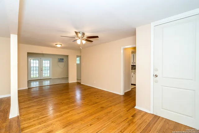 a view of an empty room with window and wooden floor