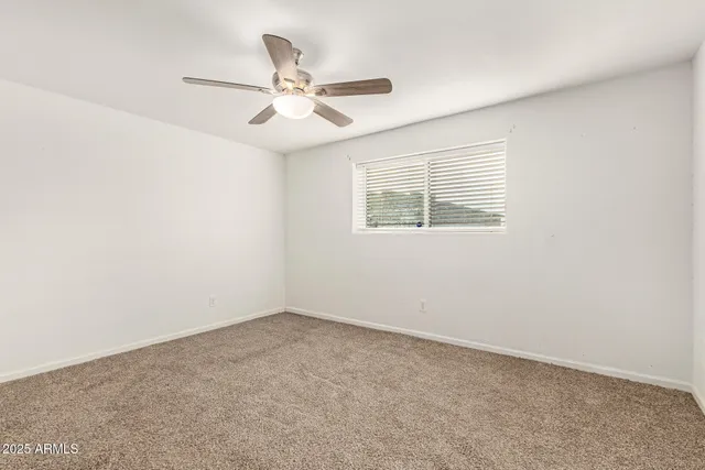 an empty room with a window and a fan