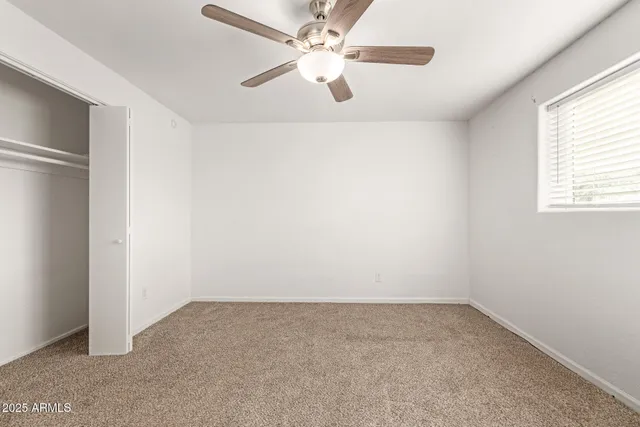 an empty room with a window and a ceiling fan