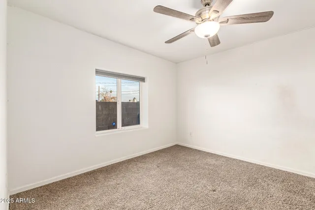 an empty room with a window and a fan