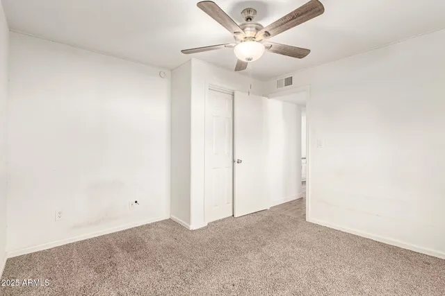 an empty room with a chandelier fan and a ceiling fan