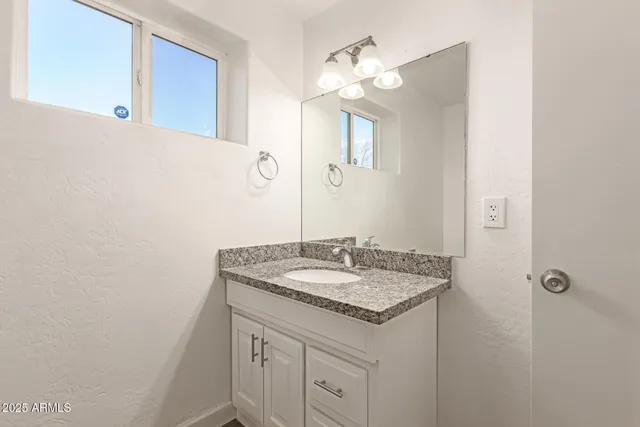 a bathroom with a granite countertop sink and a mirror