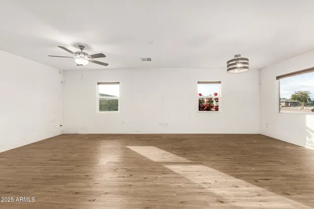 an empty room with wooden floor and ceiling fan