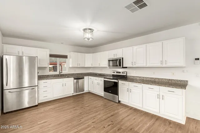 a kitchen with granite countertop white cabinets and stainless steel appliances