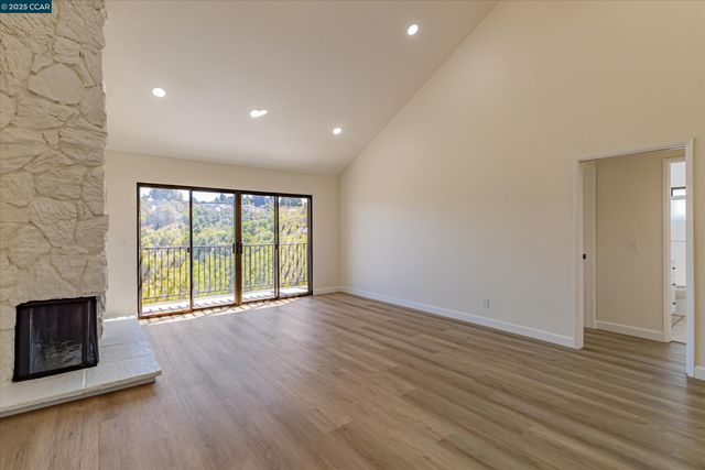 a view of an empty room with wooden floor and a fireplace