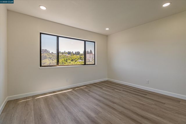a view of an empty room with wooden floor and window