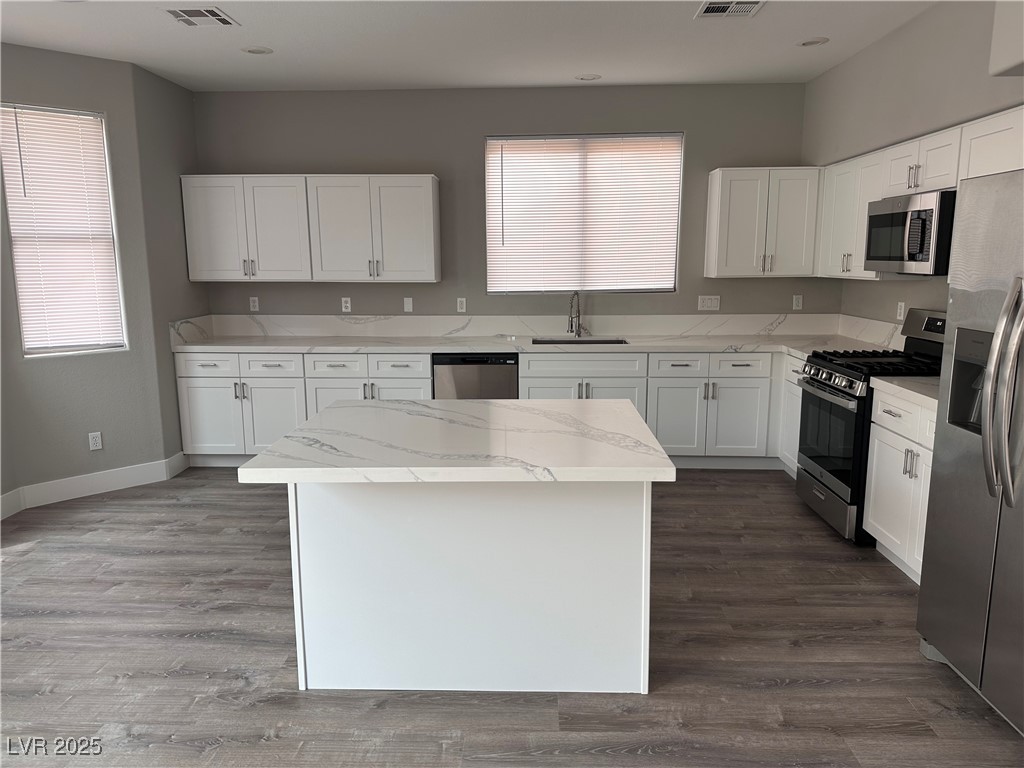 8993 Dorrell Lane Las Vegas, NV 89149 - Photo 2 of 15 Kitchen featuring appliances with stainless steel finishes, white cabinetry, light stone countertops, and healthy amount of natural light