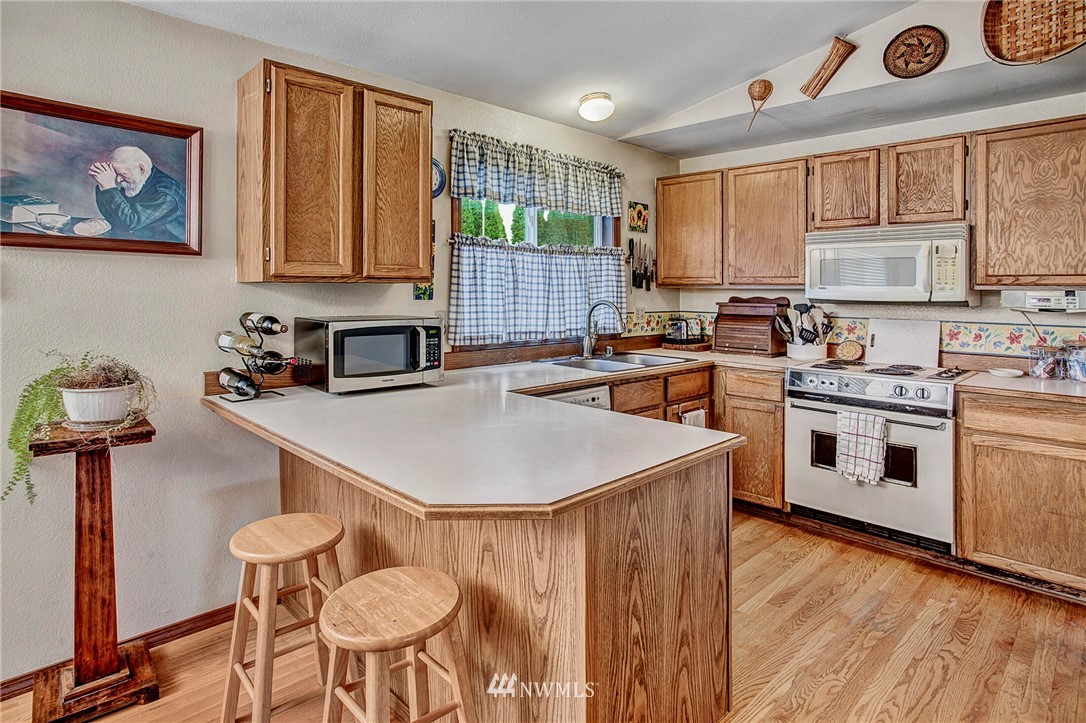 23431 12th Place West Bothell, WA 98021 - Photo 8 of 26 a kitchen with a stove a sink a microwave and cabinets
