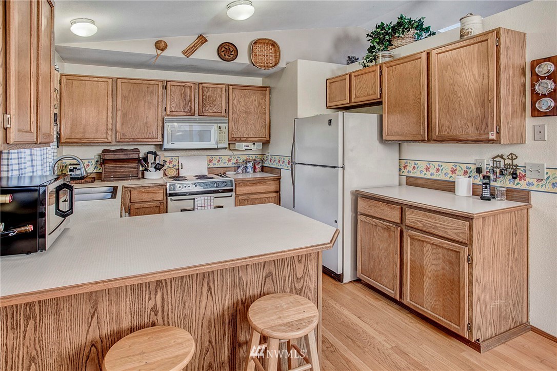 23431 12th Place West Bothell, WA 98021 - Photo 9 of 26 a kitchen with a refrigerator a stove a sink and white cabinets with wooden floor