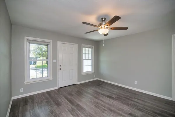 a view of an empty room with a window and wooden floor