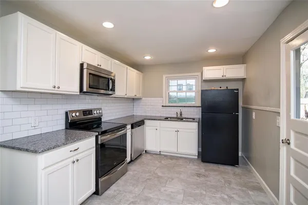 a kitchen with stainless steel appliances granite countertop a refrigerator a stove a sink a microwave a oven and grey cabinets