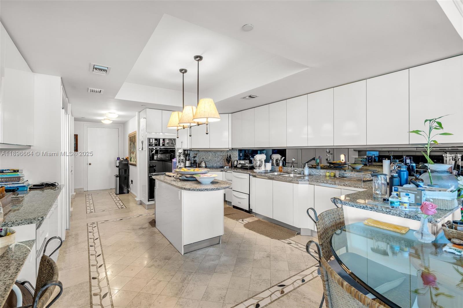 445 Grand Bay Drive, Unit 1001 Key Biscayne, FL 33149 - Photo 24 of 57 a large white kitchen with lots of counter space and chandelier