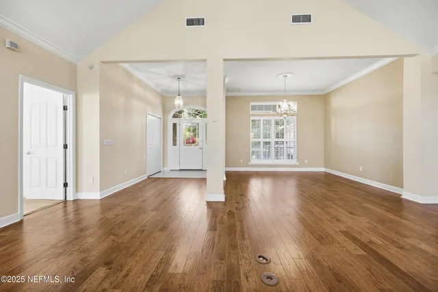 a view of an empty room with wooden floor and fireplace