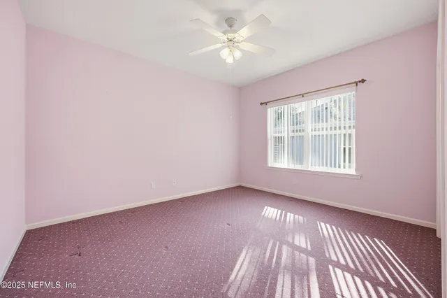 an empty room with windows and ceiling fan