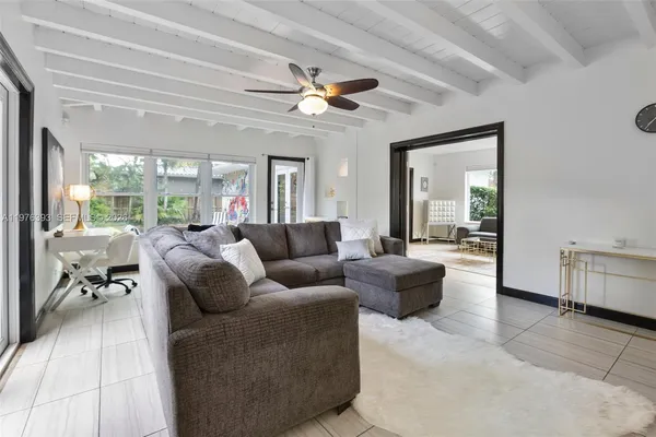 a living room with furniture a chandelier fan and a large window